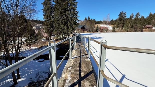 A stunningly beautiful snowy landscape showcases a winding pathway and tall trees beneath a bright clear blue sky