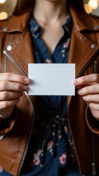 A woman in a brown leather jacket holds a blank white card, surrounded by soft indoor lighting, creating a cozy atmosphere for conversation. Card mockup concept. Generative AI.