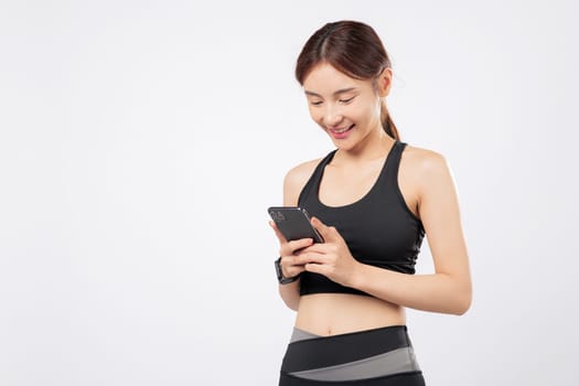 With her phone ready and her phone open to a workout app, this strong woman smiles confidently in sporty attire, blending gym life and modern mobile technology. isolated studio white background