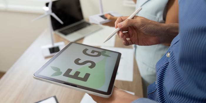 A professional reviewing ESG proposals and goals on a tablet in the office, emphasizing a commitment to sustainability and green initiatives.