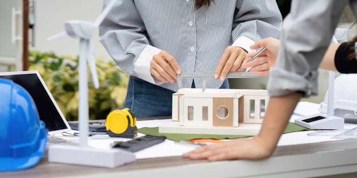 Engineers work together on a sustainable house model, adjusting features and discussing innovative solutions for eco-friendly construction.