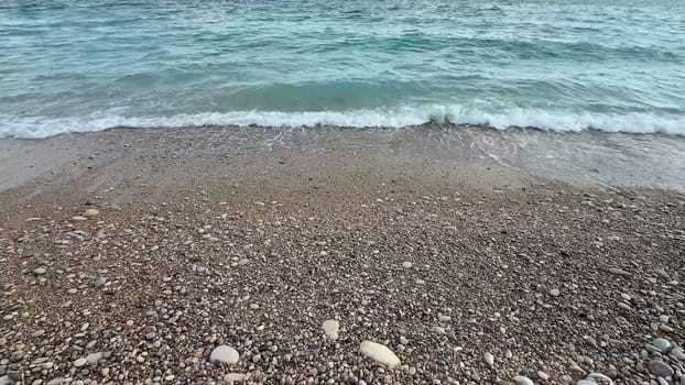 A beautifully calm beach scene that showcases the soft waves gently lapping against a pebblestrewn shore