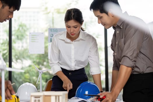 Engineers reviewing architectural models to ensure sustainable building practices, fostering teamwork and innovation.