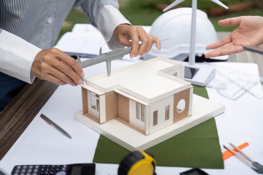 Engineers collaborate to accurately measure a sustainable building model, focusing on eco-friendly design and innovative architecture.