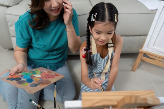 A mother and daughter painting together, exploring their creativity and enjoying a fun artistic experience.
