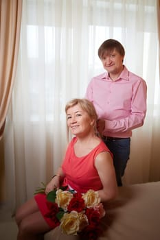 Couple enjoys a special moment capturing their love in a cozy hotel room, surrounded by flowers for Valentine's Day.