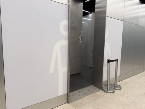 Public restroom entrance with large male and female symbols on metal wall panels in modern indoor space. Provides clear access to hygienic toilet facilities for all visitors
