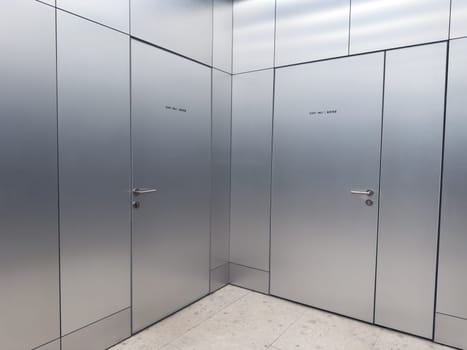 Metal doors with staff only signs in a modern public facility. Clean corridor with minimalistic design and restricted access area. Concept of security, maintenance and controlled entry
