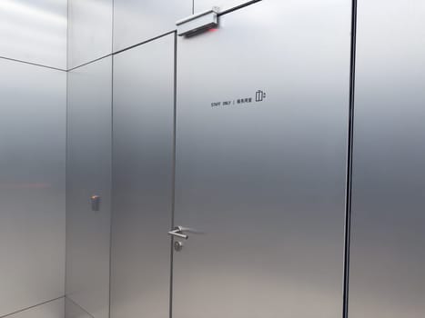 Closed metallic elevator door with staff only sign and lift symbol in modern building. Restricted access to service elevator. Concept of staff regulation, workplace security and controlled zones
