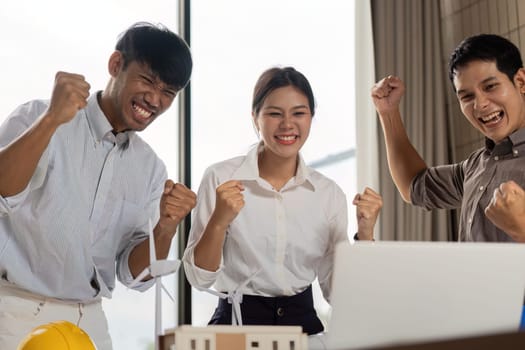 A diverse group of engineers joyfully celebrating their successful project completion in the office, expressing happiness and teamwork.