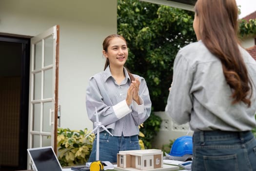 Two sustainability engineers engage in discussion about their architectural project outdoors, showcasing teamwork and creativity.