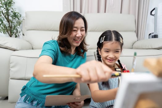 A joyful mother and daughter having fun painting together, fostering creativity in their home environment.