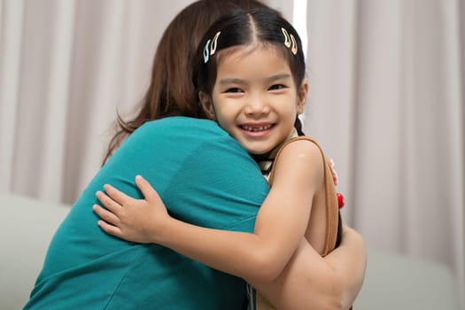 A joyful moment captures a mother hugging her daughter, radiating affection and love in a cozy indoor setting.
