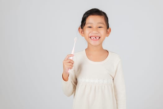 A kid with a missing tooth holds a toothbrush happily. The dentist discusses tooth loss, helping children learn a good dental care routine for healthy teeth. isolated white background