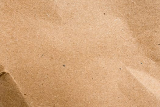 Close up of brown textured paper surface with subtle creases.