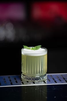 The blurred background features hues of blue and purple with bokeh lights, a stylish bar