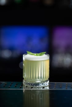 The blurred background features hues of blue and purple with bokeh lights, a stylish bar