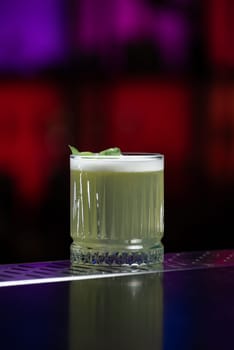 The blurred background features hues of blue and purple with bokeh lights, a stylish bar