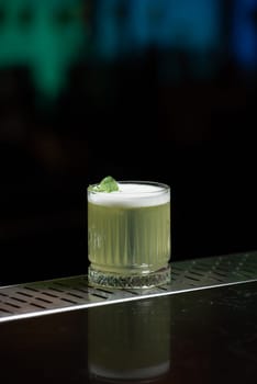 The blurred background features hues of blue and purple with bokeh lights, a stylish bar