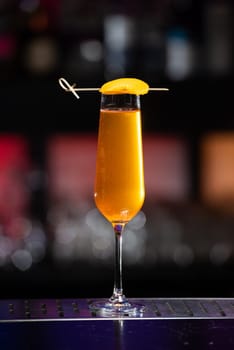 The blurred background features a colorful mix of red, purple, and green, suggesting a lively bar or event setting