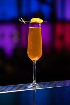 The blurred background features a colorful mix of red, purple, and green, suggesting a lively bar or event setting