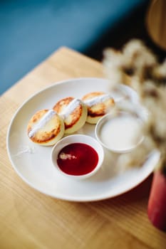 Plate Of Fluffy Pancakes With Strawberry Sauce And Cream Served On Wooden Table