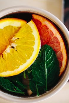 Refreshing Herbal Beverage with Orange and Grapefruit Slices and Fresh Mint Leaves in a Cup