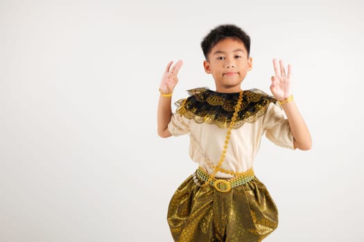 Portrait Thailand kid boy smiling traditional Thai dress costume showcases the OK sign with smile, conveying agreement and positivity, studio isolated white background, primary child success sign