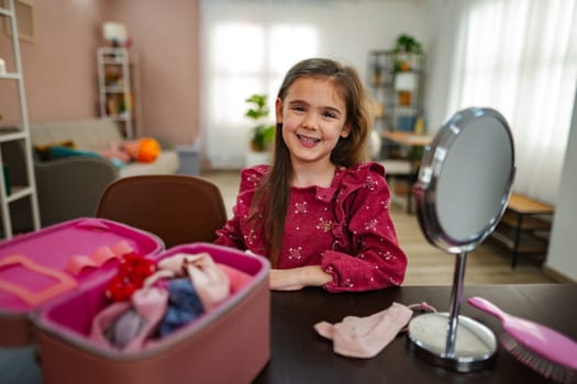 A cheerful young girl sits at a table in her bright, inviting home, exploring her colorful accessories and preparing for a fun activity, showcasing her vibrant personality and imagination.