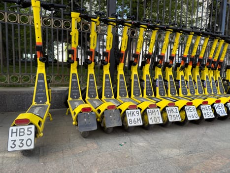 Moscow, Russia, April 24, 2025: Line of Yandex Go yellow electric scooters parked by sidewalk, representing urban mobility service by major Russian tech company in central Moscow