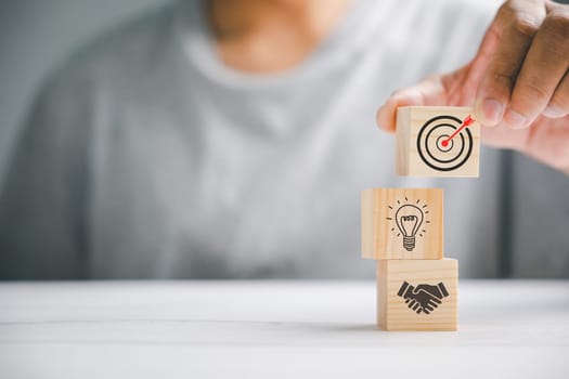 Wood block stacking by hand, symbolizing the implementation of a business strategy and action plan. Targeting the business concept. Conceptual image of success and growth.