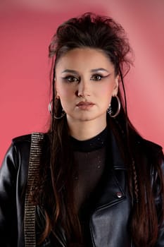 A trendy young woman with bold fashion and striking makeup poses against a vibrant, colorful background