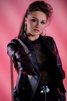 A model confidently showcases bold fashion with eyecatching leather and mesh in trendy pink lighting