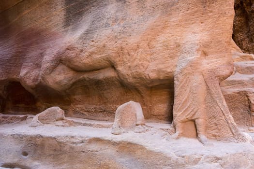 Carved camel caravan and leader along the walls of the narrow gorge of the Siq entering Petra in Jordan