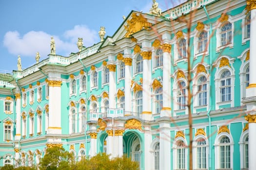 the incredibly picturesque facade of the Winter Palace through the branches of trees on a clear spring day, the heritage of Russia, the most famous landmark of St. Petersburg, the museum. High quality photo