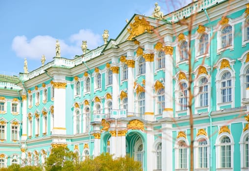 the incredibly picturesque facade of the Winter Palace through the branches of trees on a clear spring day, the heritage of Russia, the most famous landmark of St. Petersburg, the museum. High quality photo