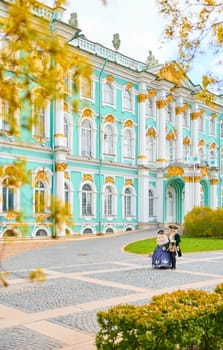 Russia, St. Petersburg, 10 May 2025: the incredibly picturesque facade of the Winter Palace through the branches of trees on a clear spring day, actors in tsarist outfits, the heritage of Russia. High quality photo