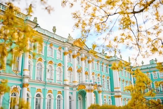 the incredibly picturesque facade of the Winter Palace through the branches of trees on a clear spring day, the heritage of Russia, the most famous landmark of St. Petersburg, the museum. High quality photo