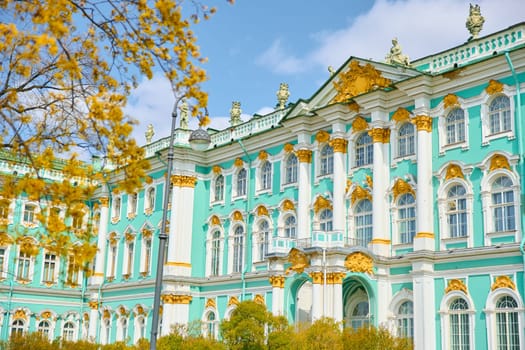 the incredibly picturesque facade of the Winter Palace through the branches of trees on a clear spring day, the heritage of Russia, the most famous landmark of St. Petersburg, the museum. High quality photo