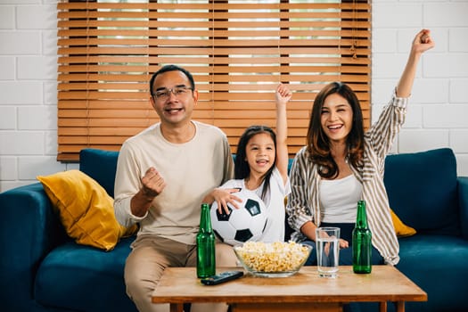 In their living room, a joyful family of fans bonds over a football match on TV, celebrating their team's success with cheers and excitement. The room is filled with togetherness and happiness.