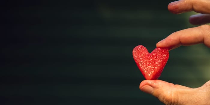 Summer seasonal food. Juicy red watermelon slice cut in heart shape outdoors summertime holidays sunbeams. Concept of enjoying the moment in fresh air. Sustainable calm lifestyle pastoral life cottagecore escapism