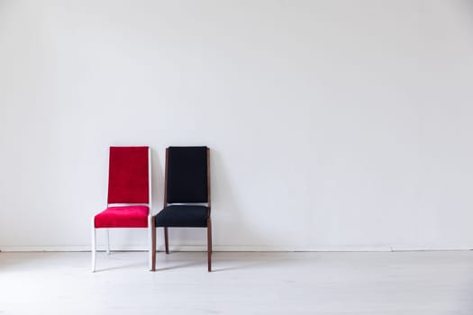 Two old chairs red and black in the interior of a white room