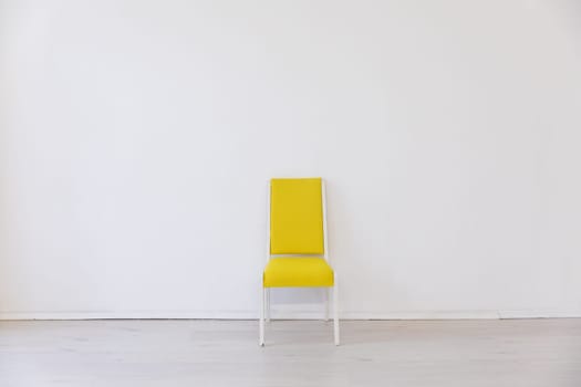 One yellow old chair in the interior of a white room near the wall