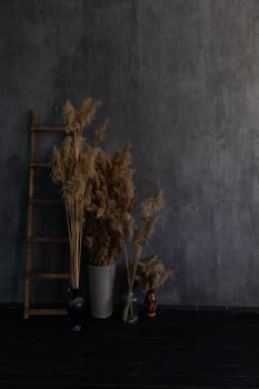 Vase with dry flowers and staircase in the interior of a dark gray room