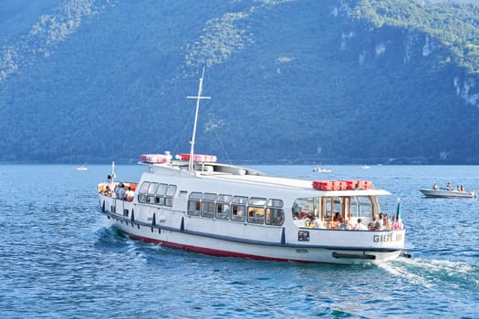Como, Italy - July 26, 2020. Cruise boat tour on lake Como. Ferry boat with many tourist on board moving at high speed in sunny summer day
