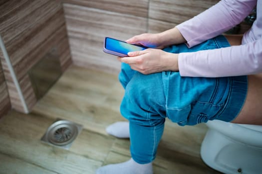 Enjoying personal time while scrolling through content in the restroom.