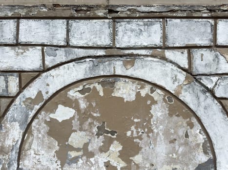 Peeling paint and rough plaster on an old brick wall form textured background with weathered surfaces and visible damage. Perfect for design or architectural texture reference