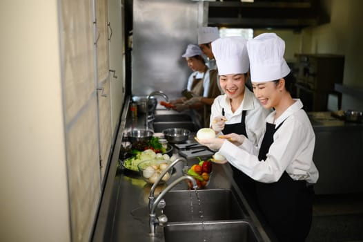 Smiling young chefs learning kitchen hygiene and teamwork in a professional cooking school.