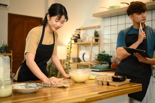 Happy couple preparing pancake batter together in a cozy kitchen.