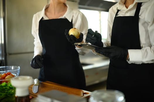 Chefs in training discussing produce quality while documenting kitchen prep procedures.